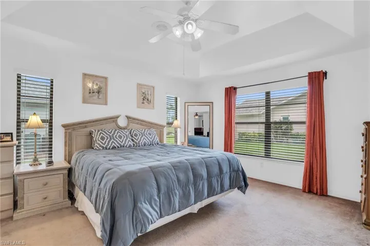 Carpeted bedroom with a coffered ceiling, multiple windows, and ceiling fan
