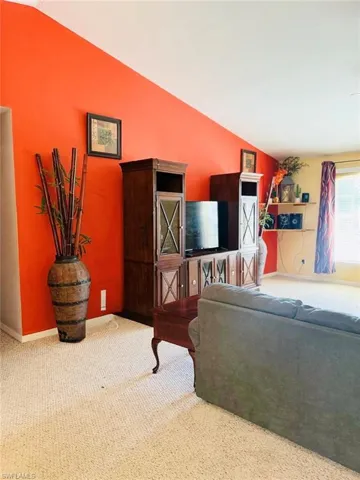 Carpeted living area with lofted ceiling and baseboards
