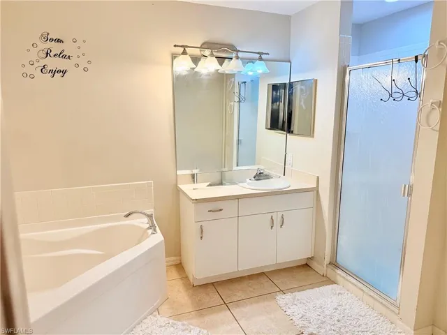 Bathroom featuring a garden tub, a shower stall, vanity, and light tile patterned floors