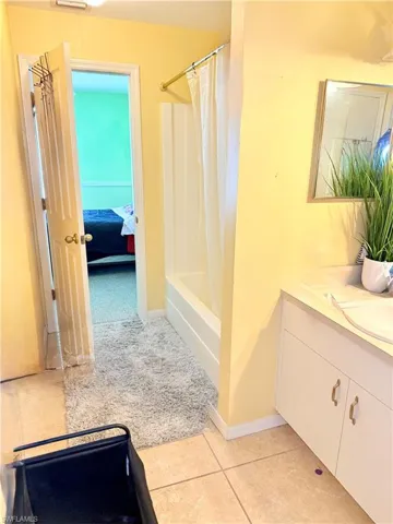 Bathroom featuring vanity, connected bathroom, shower / bath combo, and light tile patterned floors