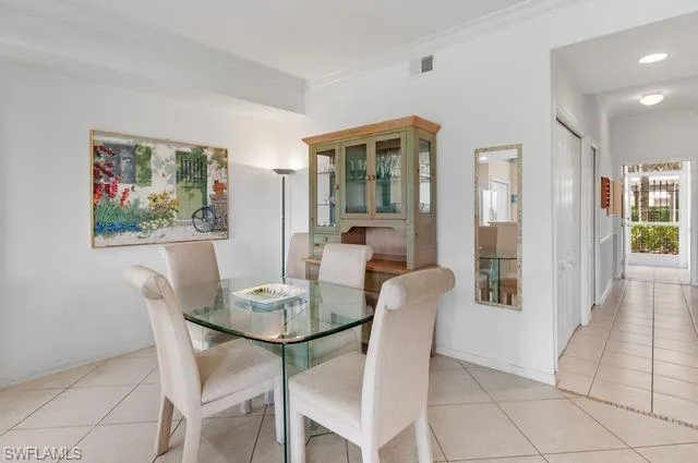 Dining area with light tile patterned flooring and crown molding