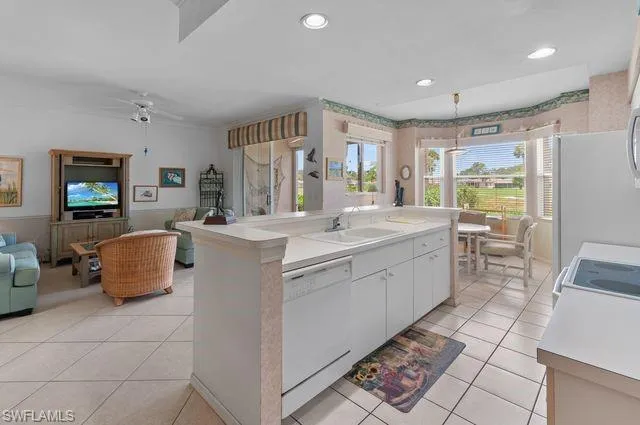 Kitchen featuring dishwasher, light tile patterned flooring, open floor plan, light countertops, and white cabinetry