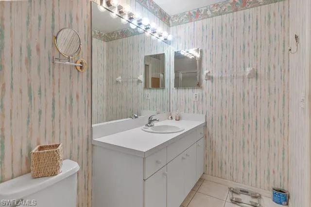 Bathroom with wallpapered walls, vanity, and tile patterned floors
