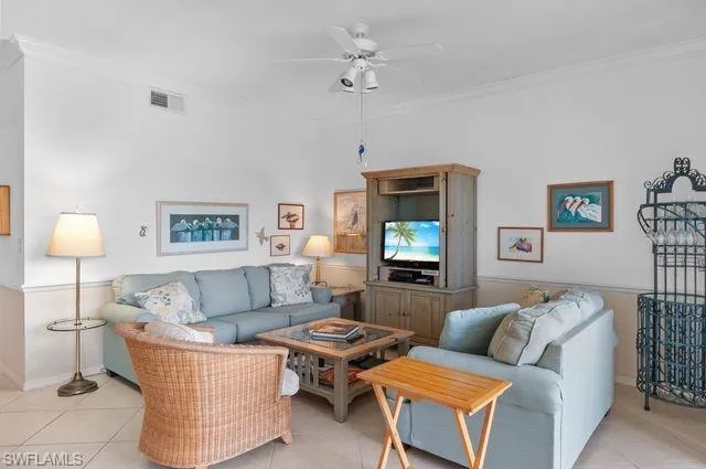Living room with light tile patterned floors, a ceiling fan, and crown molding