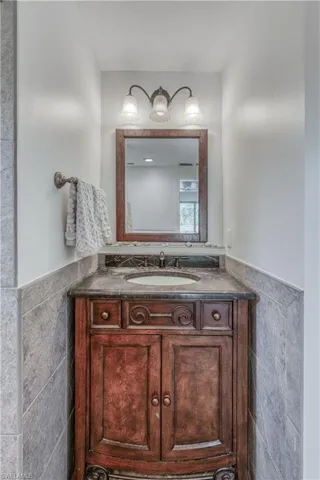 Bathroom featuring vanity, a wainscoted wall, and tile walls