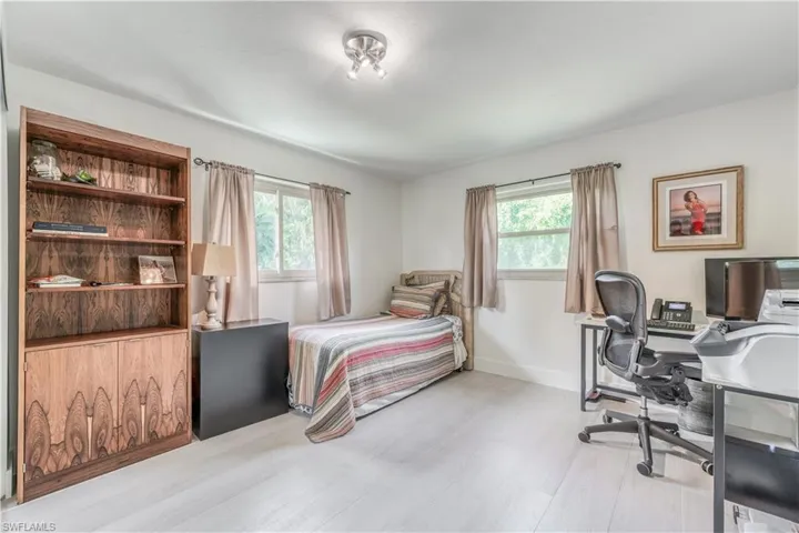 Bedroom featuring baseboards, multiple windows, and light wood-style flooring