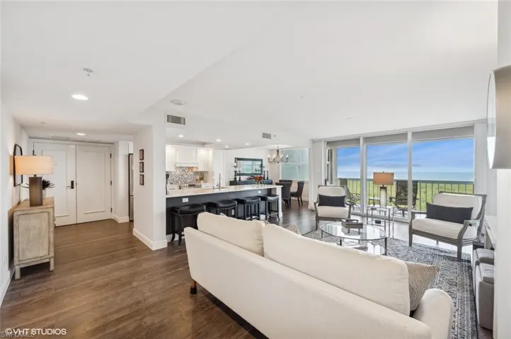 Living room with sink, dark wood-type flooring, and a notable chandelier