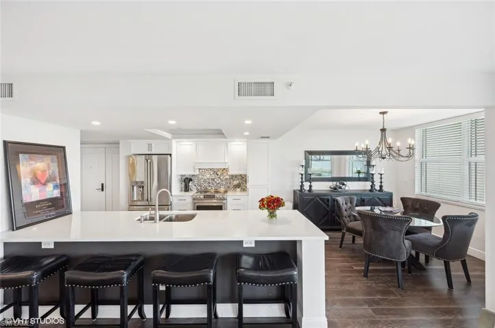 Kitchen with sink, dark wood-type flooring, an inviting chandelier, high quality appliances, and white cabinets