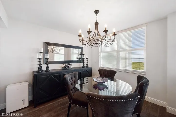 Dining room featuring dark hardwood / wood-style flooring, an inviting chandelier, and a healthy amount of sunlight