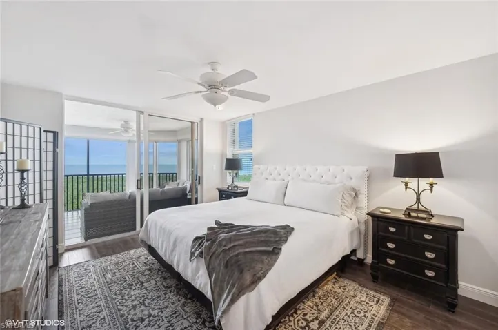 Bedroom featuring access to exterior, a water view, ceiling fan, and dark wood-type flooring