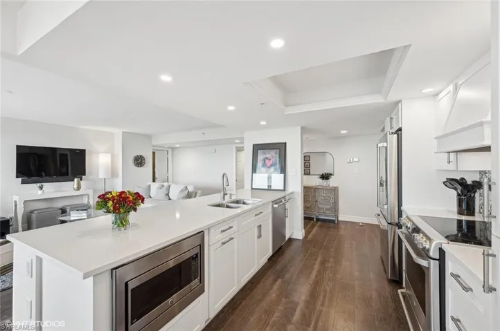 Kitchen featuring white cabinets, a center island with sink, sink, dark hardwood / wood-style floors, and stainless steel appliances