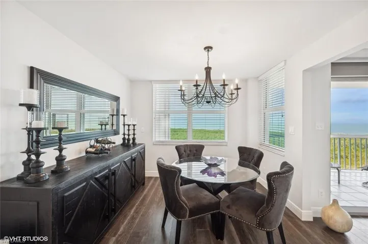 Dining area with dark hardwood / wood-style flooring, a wealth of natural light, and a notable chandelier