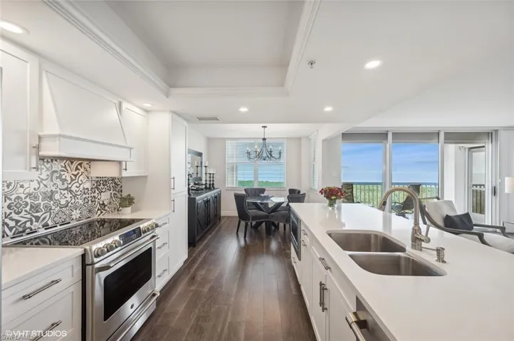 Kitchen with a wealth of natural light, white cabinetry, sink, high end range, and custom range hood