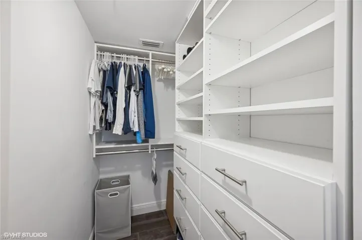 Walk in closet with dark wood-type flooring