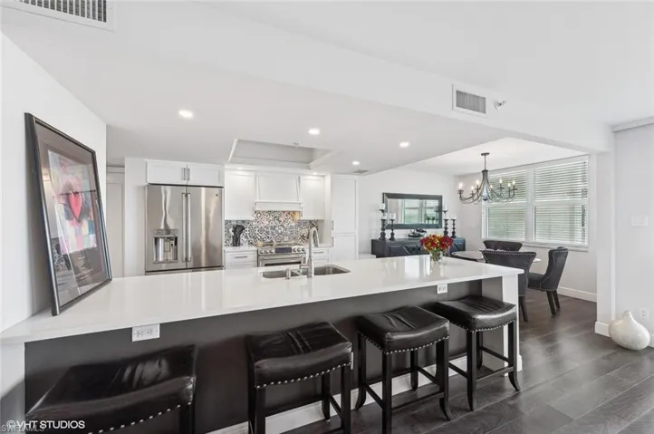 Kitchen with sink, dark hardwood / wood-style floors, high end fridge, a kitchen bar, and white cabinetry