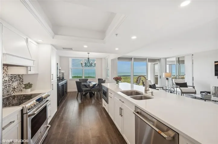 Kitchen with stainless steel appliances, sink, decorative light fixtures, dark hardwood / wood-style floors, and white cabinetry