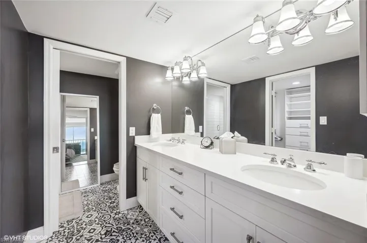 Bathroom featuring tile patterned flooring, vanity, toilet, and a notable chandelier