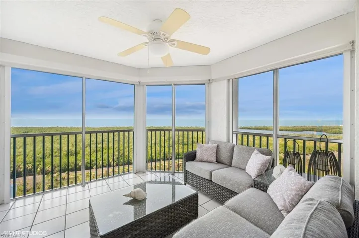 Sunroom / solarium with ceiling fan and a water view