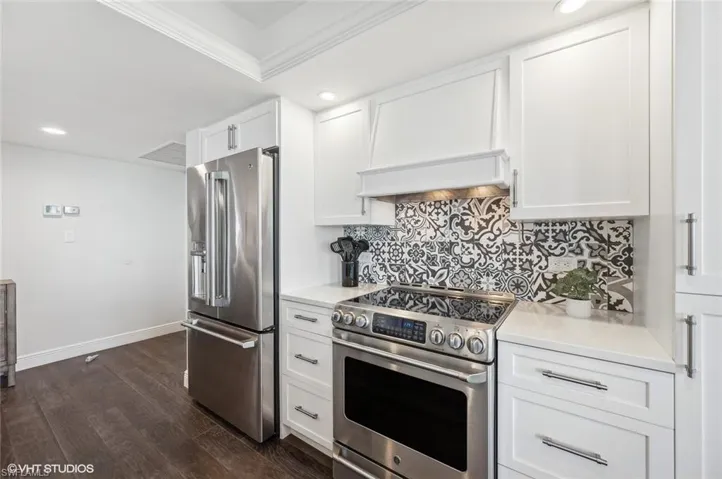 Kitchen featuring custom exhaust hood, high end appliances, white cabinets, ornamental molding, and dark hardwood / wood-style flooring