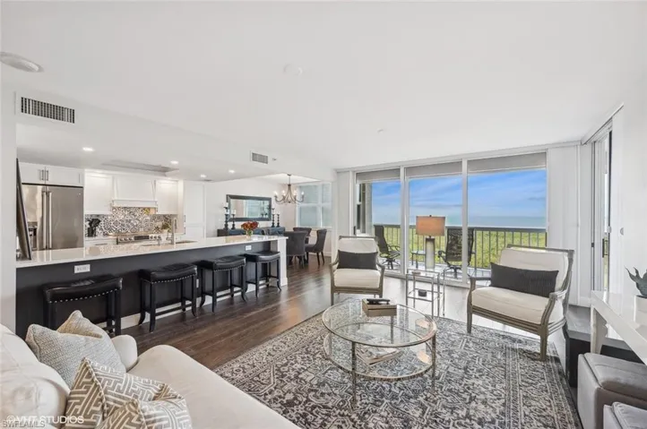Living room with dark hardwood / wood-style floors, floor to ceiling windows, and a notable chandelier