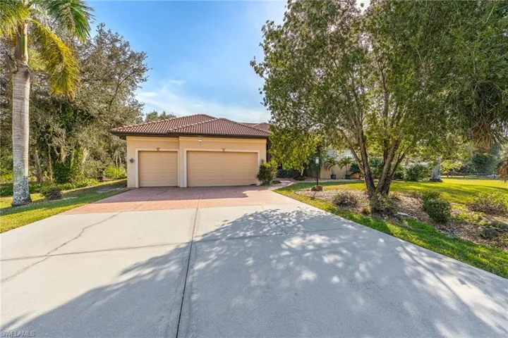 View of front of home with a front yard and a three car garage.