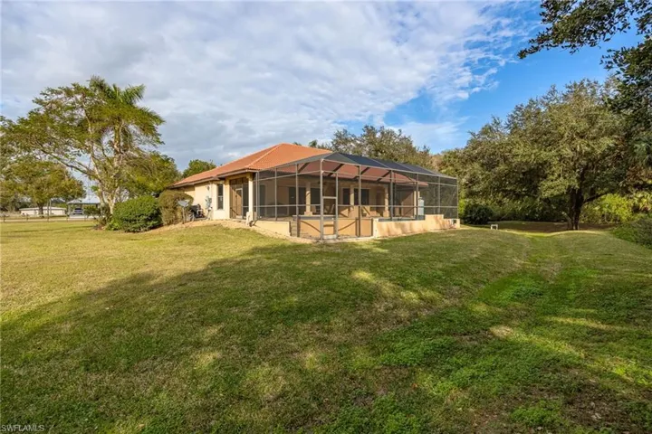 Back of house with a yard and a screened lanai
