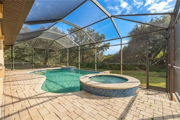 View of swimming pool with 3 swim up bar seats and spa.