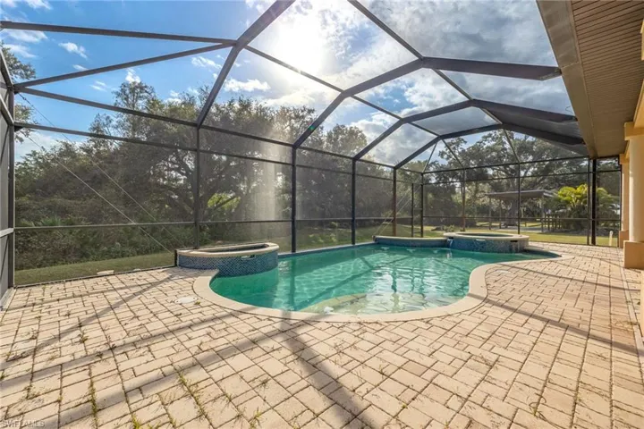 View of swimming pool with an in ground hot tub, a patio area, and a lanai