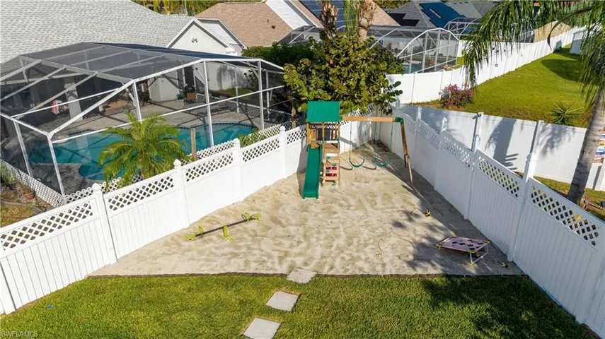 Fenced backyard with a sunroom, a playground, a lanai, and a patio area