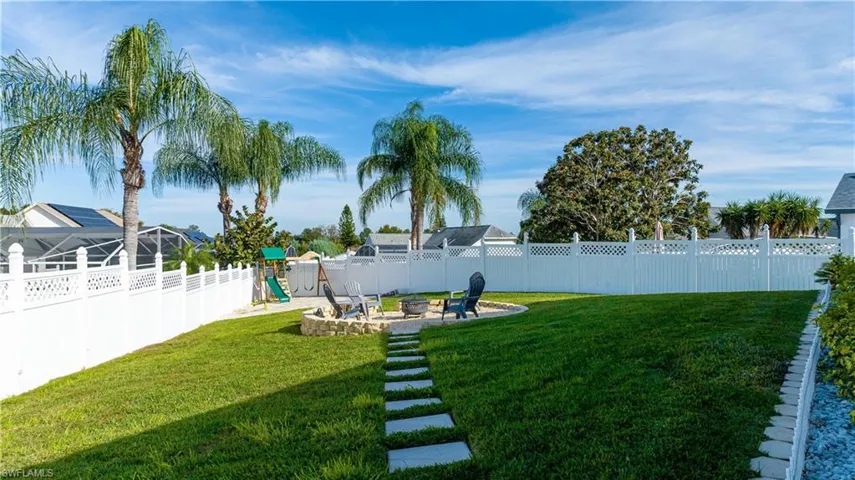 Fenced backyard featuring a playground, a patio, and a fire pit