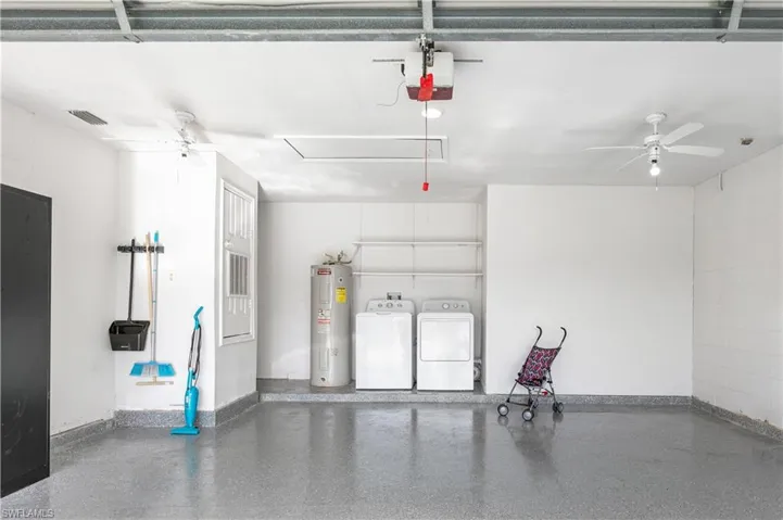Garage with ceiling fan, electric water heater, independent washer and dryer, and a garage door opener