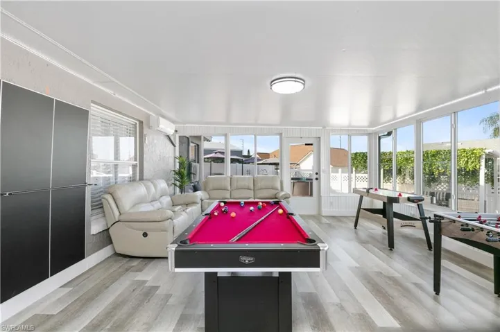 Game room with light wood-style floors, healthy amount of natural light, pool table, and a wall mounted air conditioner