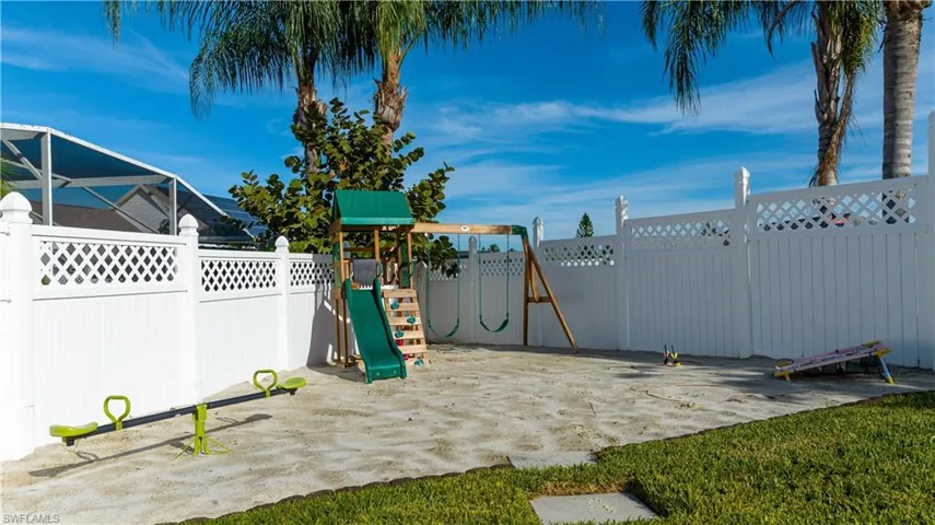 View of jungle gym featuring a fenced backyard and glass enclosure