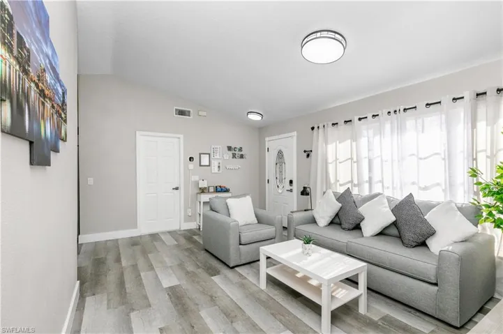 Living area with vaulted ceiling and light wood-style flooring