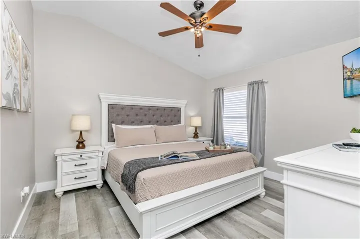 Bedroom with vaulted ceiling, light wood-style flooring, and a ceiling fan