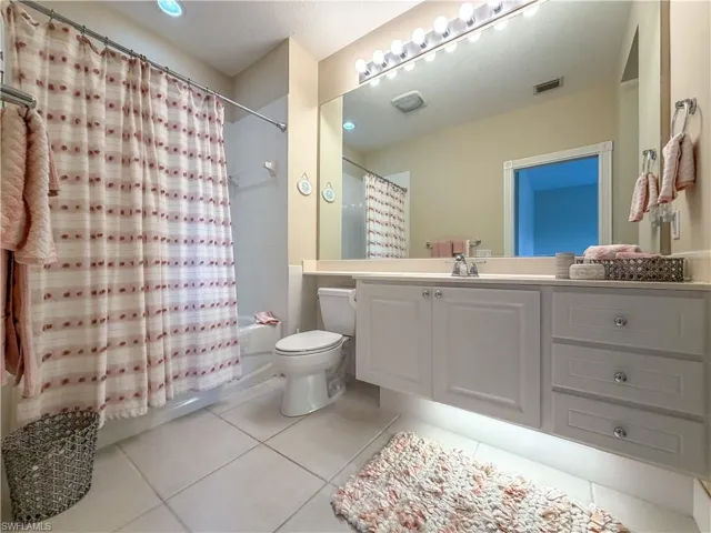 Bathroom featuring vanity, shower / tub combo with curtain, and light tile patterned floors