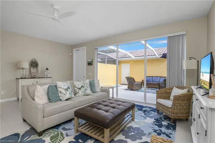 Living area featuring a ceiling fan, light tile patterned floors, and a sunroom