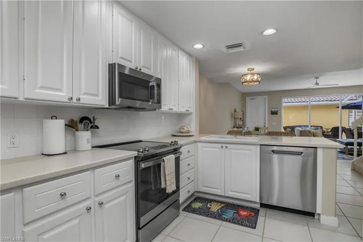 Kitchen featuring stainless steel appliances, white cabinetry, a peninsula, light countertops, and recessed lighting