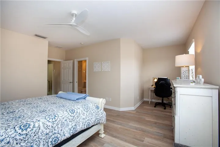 Bedroom with light wood-type flooring, an office area, and a ceiling fan