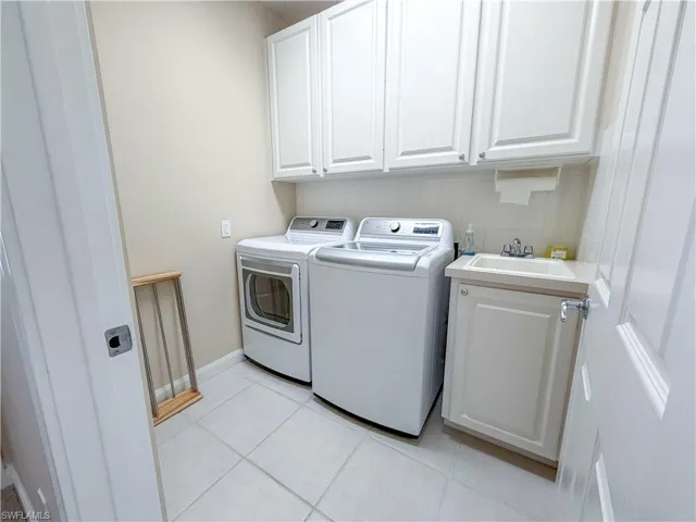 Laundry area featuring cabinet space, light tile patterned flooring, and washing machine and dryer