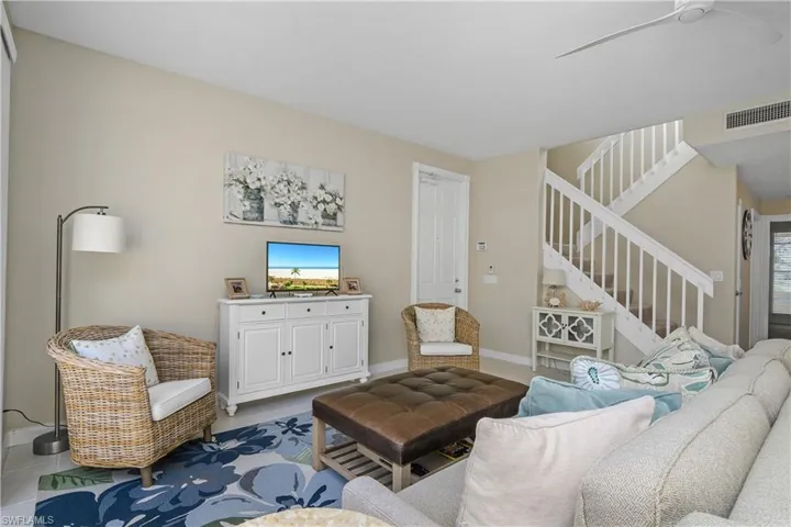 Tiled living room with stairway and ceiling fan