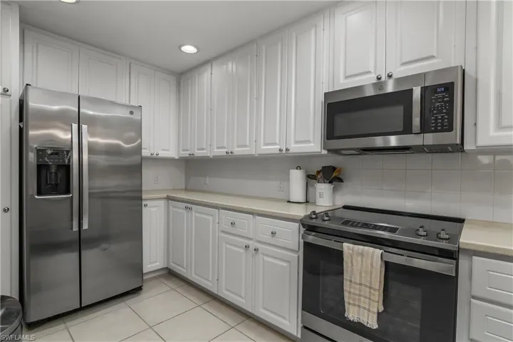 Kitchen featuring stainless steel appliances, light countertops, white cabinetry, light tile patterned floors, and recessed lighting