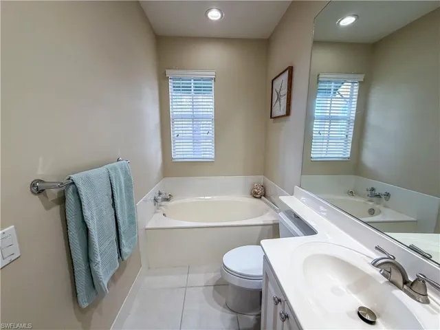 Bathroom featuring a garden tub, vanity, light tile patterned floors, and recessed lighting