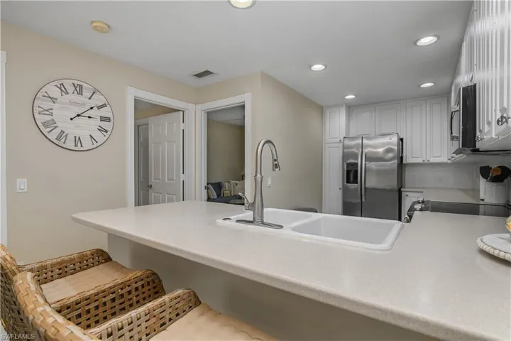 Kitchen with a breakfast bar area, recessed lighting, stainless steel appliances, light countertops, and a peninsula