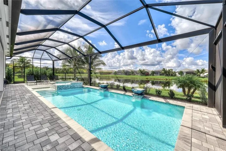 View of swimming pool featuring pool water feature, an in ground hot tub, a lanai, a water view, and a patio