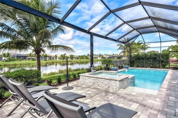 View of pool with an in ground hot tub, a water view, a patio area, and a lanai