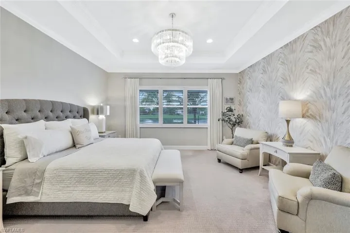 Bedroom with ornamental molding, an inviting chandelier, carpet floors, and a raised ceiling