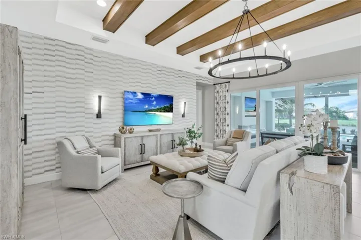 Living room with beamed ceiling, an inviting chandelier, and light tile patterned floors