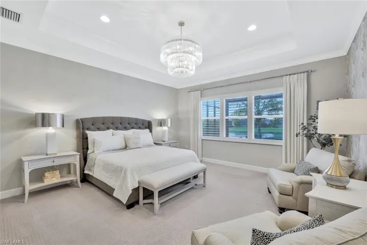 Bedroom featuring crown molding, a raised ceiling, light colored carpet, and a chandelier