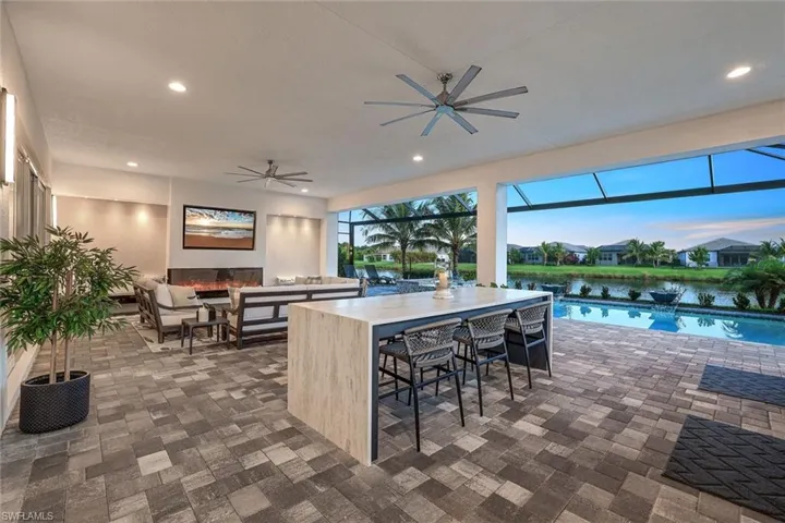 Patio terrace at dusk with a water view, an outdoor bar, and ceiling fan